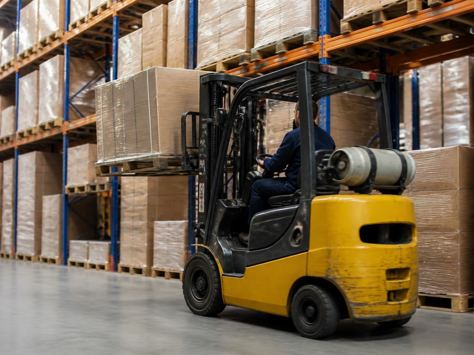 Forklift moving pallets through warehouse racking